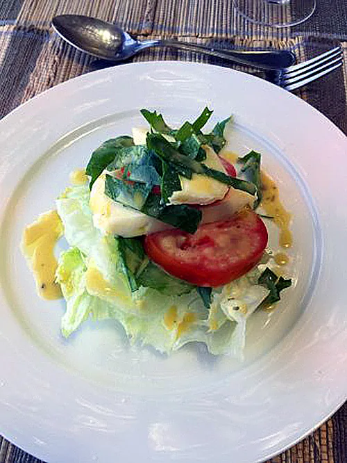 Fresh salad with lettuce, tomato, and sliced radish on a white plate at Kaboso Safari Camp.